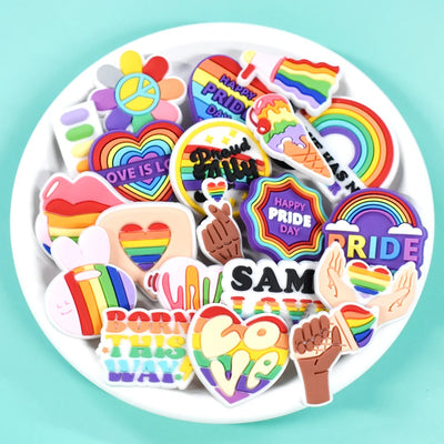 Collection of colorful Pride-themed shoe charms on a white plate with a light blue background