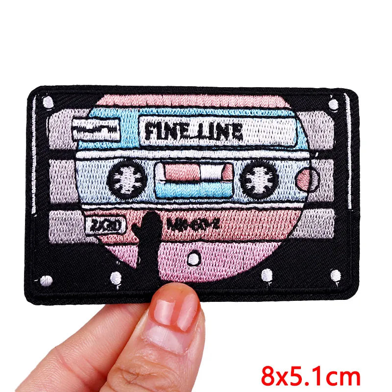 Cassette tape-shaped patch held by a hand with 'Fine Line' branding.