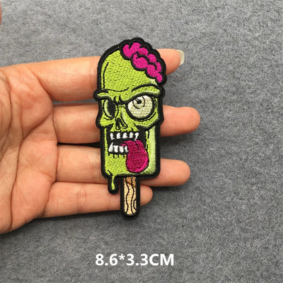 Zombie ice cream patch held between fingers on a gray background