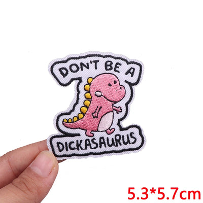 Pink dinosaur patch with text 'Don't be a Dickasaurus' held by a hand on a white background.