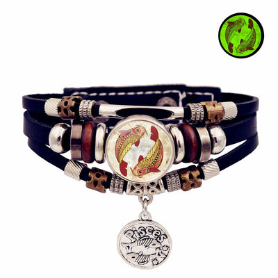 Multilayered bracelet with fish charm and black leather strap on a white background
