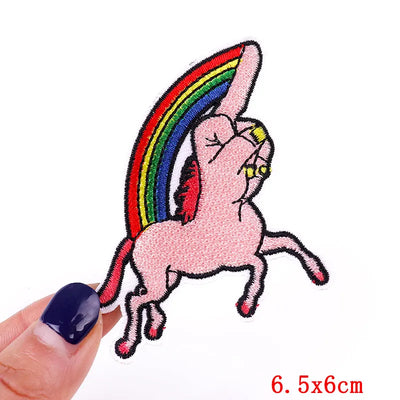 Pink cartoon horse with rainbow tail held by a hand on a white background
