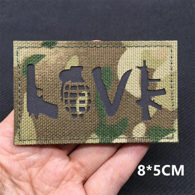 Camouflage patch with 'LOVE' design held in a hand against a dark background