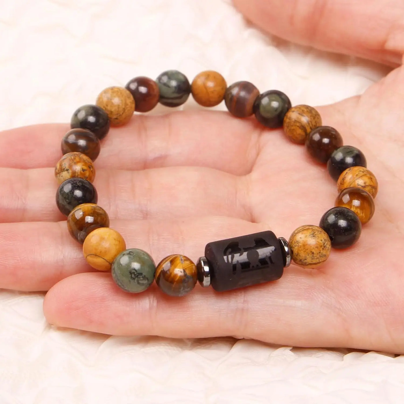 Beaded bracelet with a black focal bead on a hand against a white background