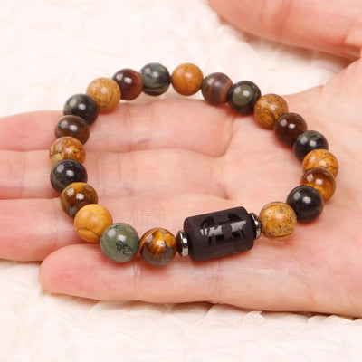 Beaded bracelet with a black focal bead on a hand against a white background