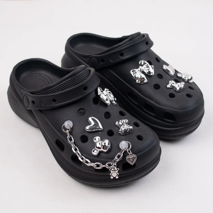 Black clogs with silver charms on a white background