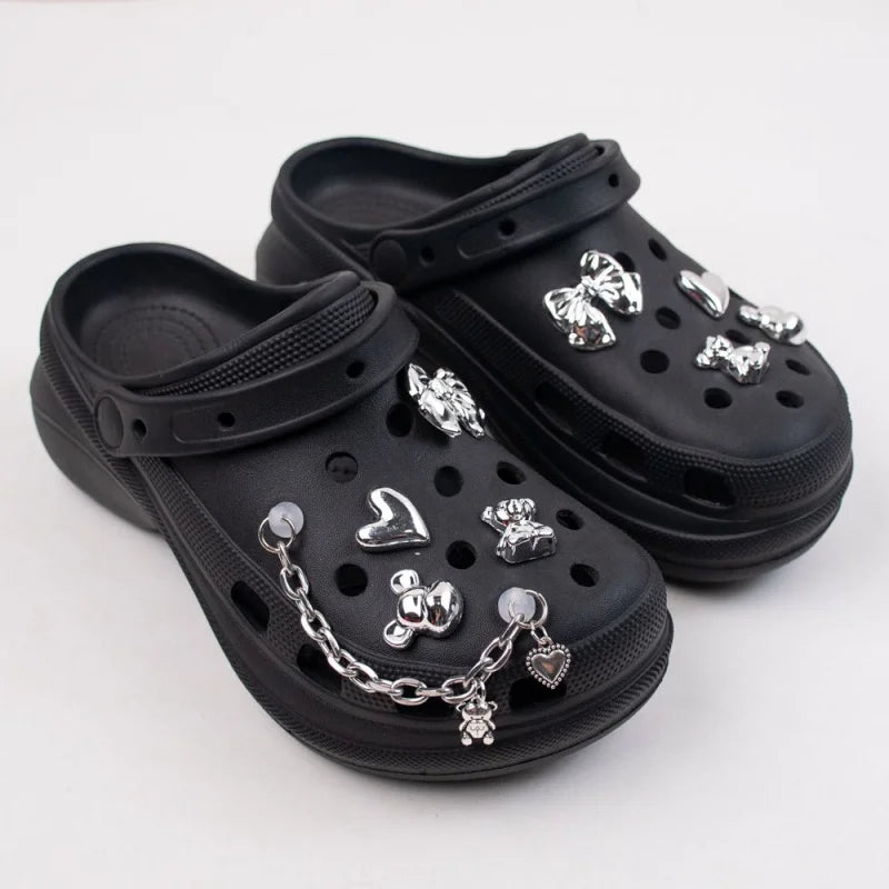 Black clogs with silver charms on a white background