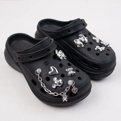 Black clogs with silver charms on a white background