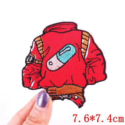Red cartoon character patch held by a finger with measurement text on a white background