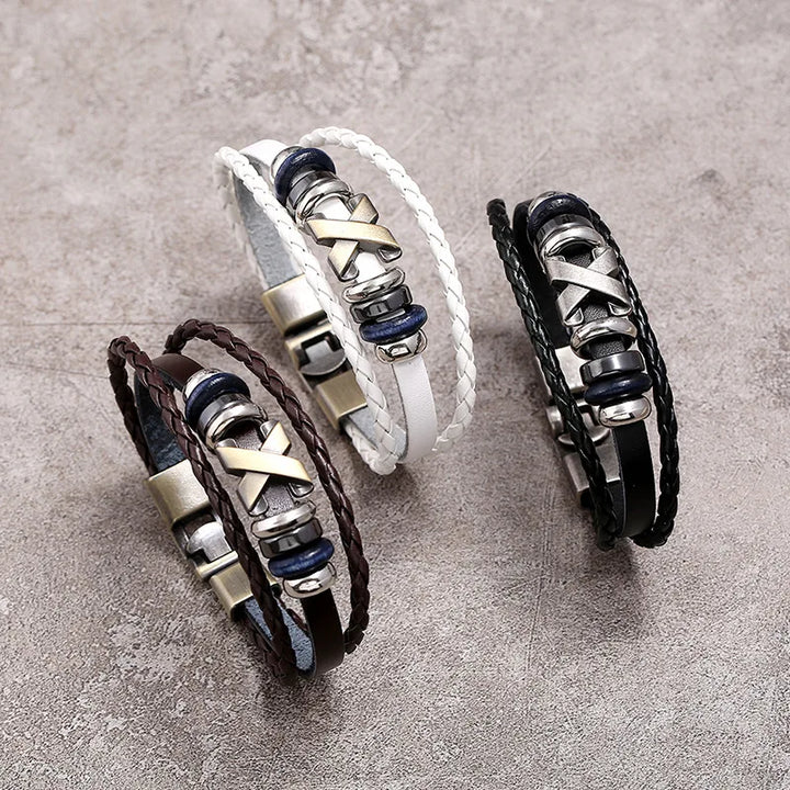 Three leather bracelets with metal accents on a gray surface