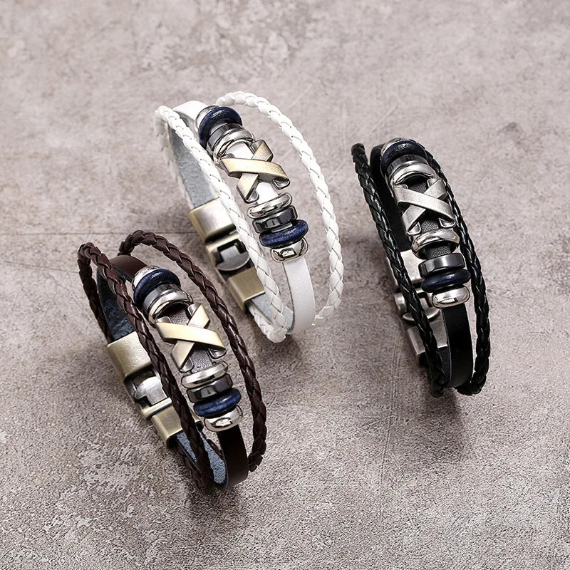 Three leather bracelets with metal accents on a gray surface