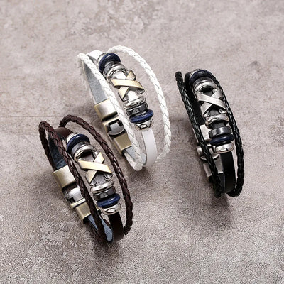 Three leather bracelets with metal accents on a gray surface