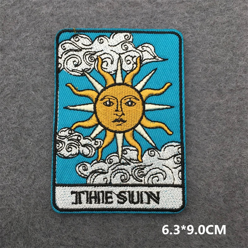 Embroidered patch of 'The Sun' tarot card design on a textured gray background