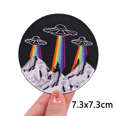 Embroidered patch with UFOs and rainbows held by a hand, size 7.3x7.3cm.