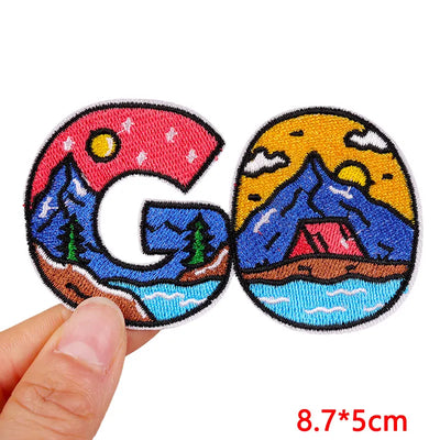Two embroidered patches with mountain and camping design held by a hand, with size '8.7*5cm' displayed.