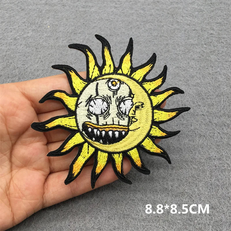 Sun-shaped patch with a face design held by a hand on a gray background
