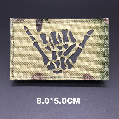 Camouflage patch with skeleton hand sign on a dark background