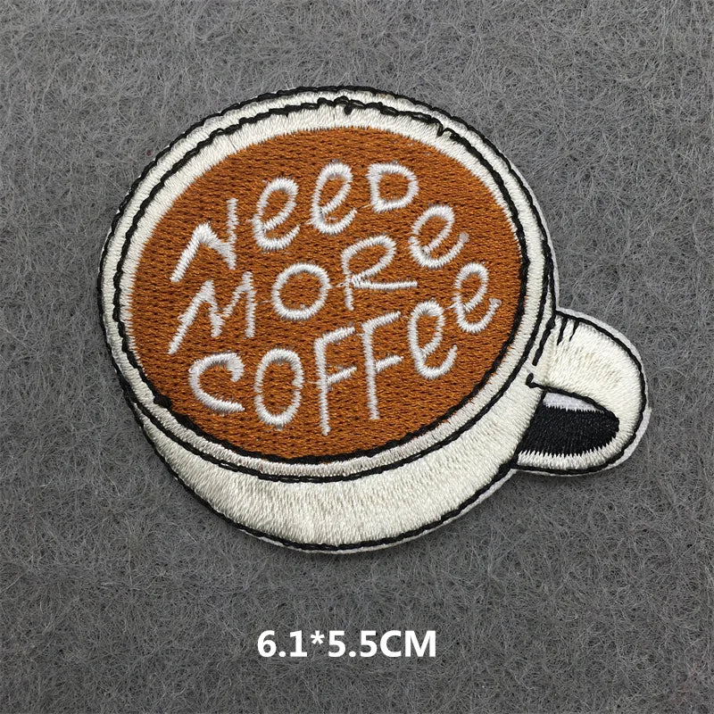 Embroidered patch of a coffee cup with 'Need More Coffee' text on a gray background