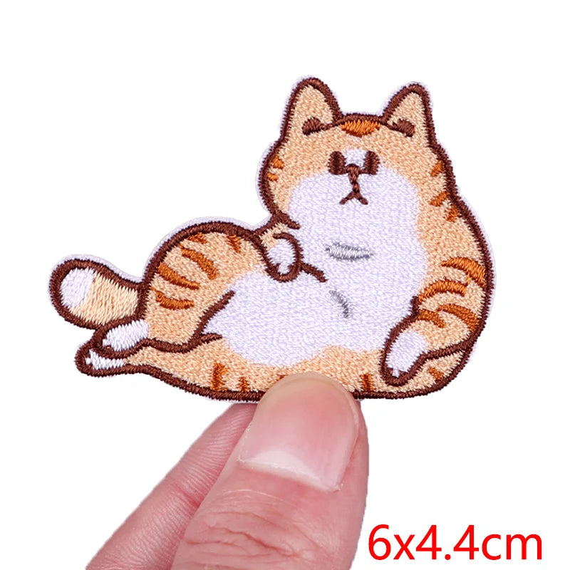 Cat-shaped patch held between a thumb and forefinger with size '6x4.4cm' displayed.