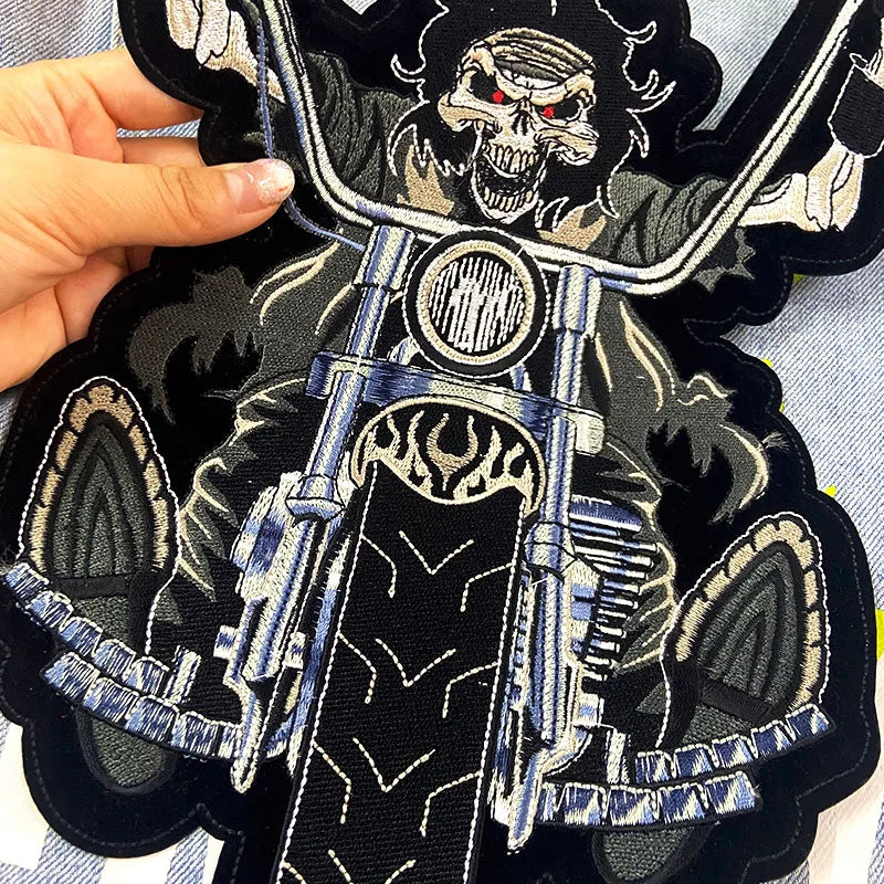 Embroidered patch of a skeleton on a motorcycle with a hand holding it.