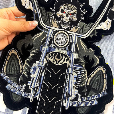 Embroidered patch of a skeleton on a motorcycle with a hand holding it.