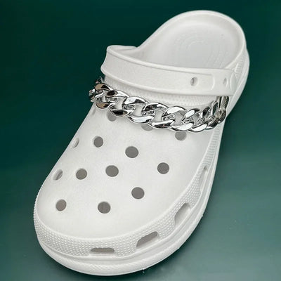 White clog shoe with a silver chain on a green background