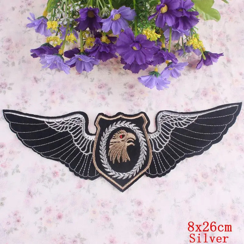 Decorative patch with wings and an eagle emblem on a floral background