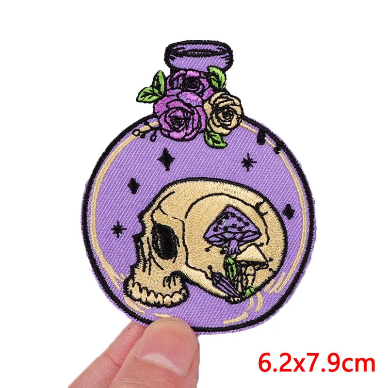 Decorative patch with skull design on a purple background held by a hand.