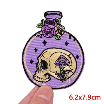Decorative patch with skull design on a purple background held by a hand.