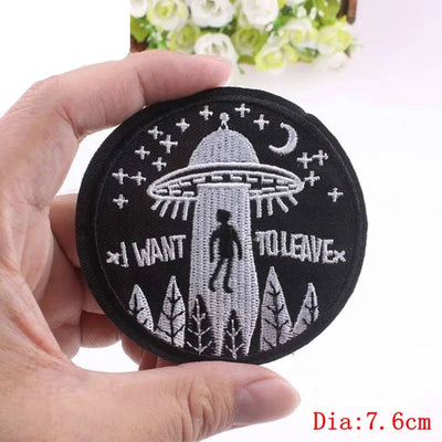 Embroidered patch with UFO design held by a hand, brand 'Prajna' visible.
