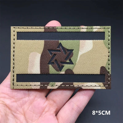 Israel flag Camouflage patch held in a hand against a dark background