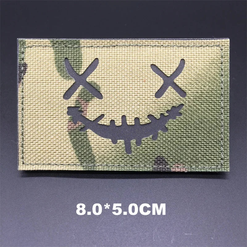 Multicam patch with a smiley face design on a dark background