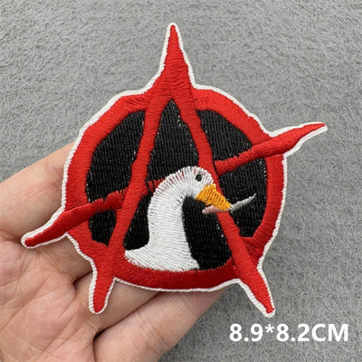 Embroidered patch with red, black, and white design held by a hand on a gray background