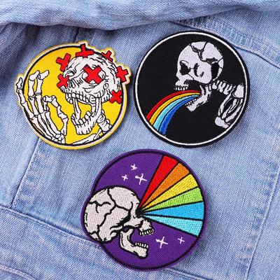 Three colorful skull-themed patches on a denim background