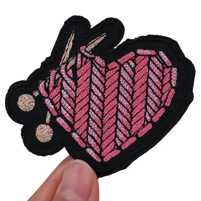 Embroidered patch with pink and black design held by a hand on a white background