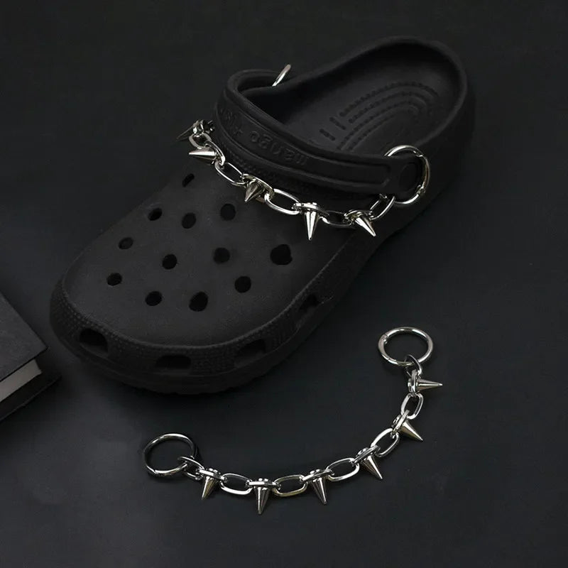 Black croc shoe with a spiked metal chain on a dark background