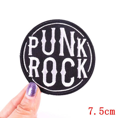 Punk Rock patch held by a hand with purple nail polish on a white background