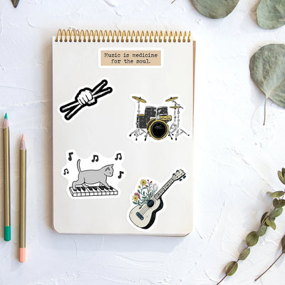 Notebook with music-themed stickers on a white surface with pencils and leaves.