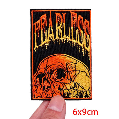 Embroidered patch with 'Fearless' text and skull design held by a hand, on a white background.