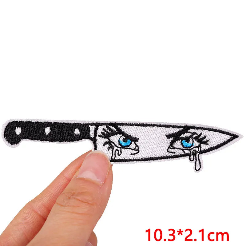Knife-shaped patch with cartoon eyes held by a hand on a white background