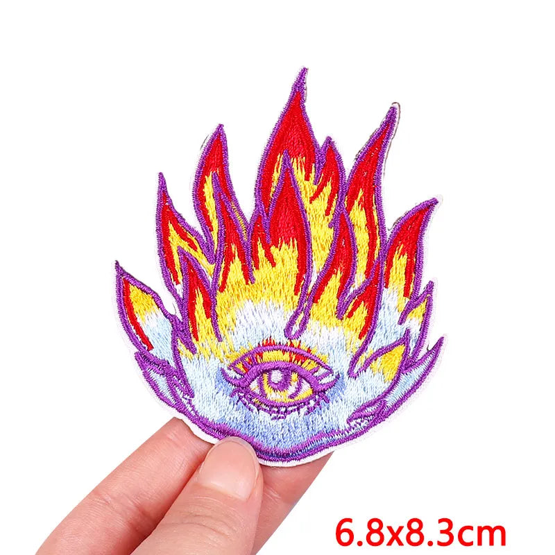 Colorful flame-shaped patch with an eye design held by a hand on a white background
