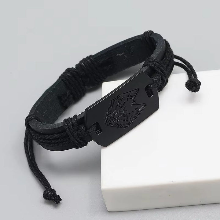 Black woven bracelet with a metal clasp featuring a wolf emblem on a white surface.