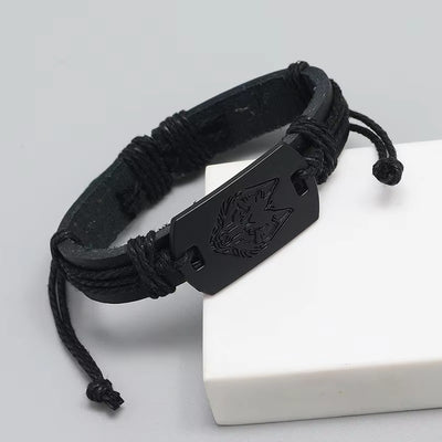 Black woven bracelet with a metal clasp featuring a wolf emblem on a white surface.