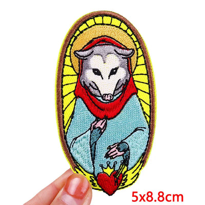 Embroidered patch of a stylized animal with a red cloth and yellow border held by a hand.