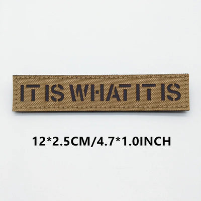 Textile patch with 'IT IS WHAT IT IS' on a white background
