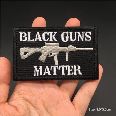 Patch with 'Black Guns Matter' text held in a hand against a dark background