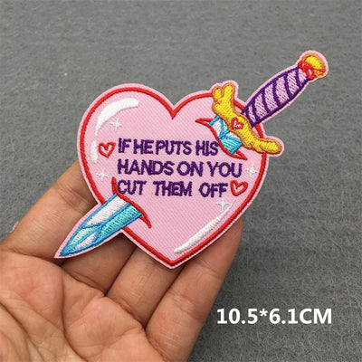 Heart-shaped patch with text and knives held in a hand on a gray background