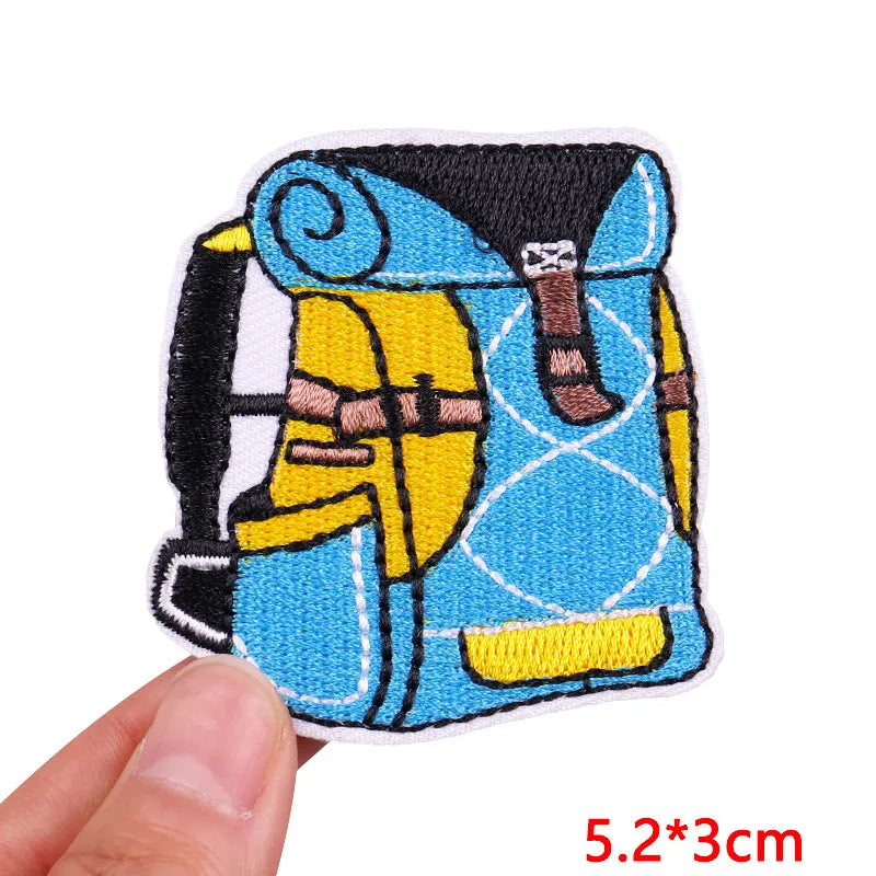 Embroidered patch of a character with a blue background held by a hand, with dimensions displayed.