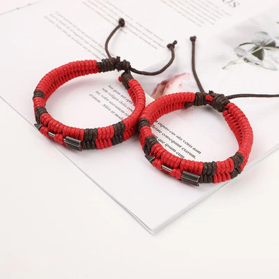 Red and black braided bracelets on a white surface with text.