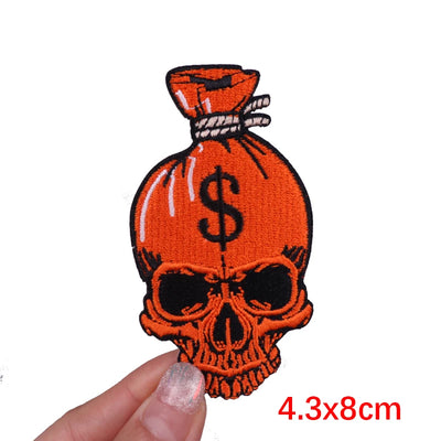 Embroidered patch of a skull with a money bag and dollar sign on a white background
